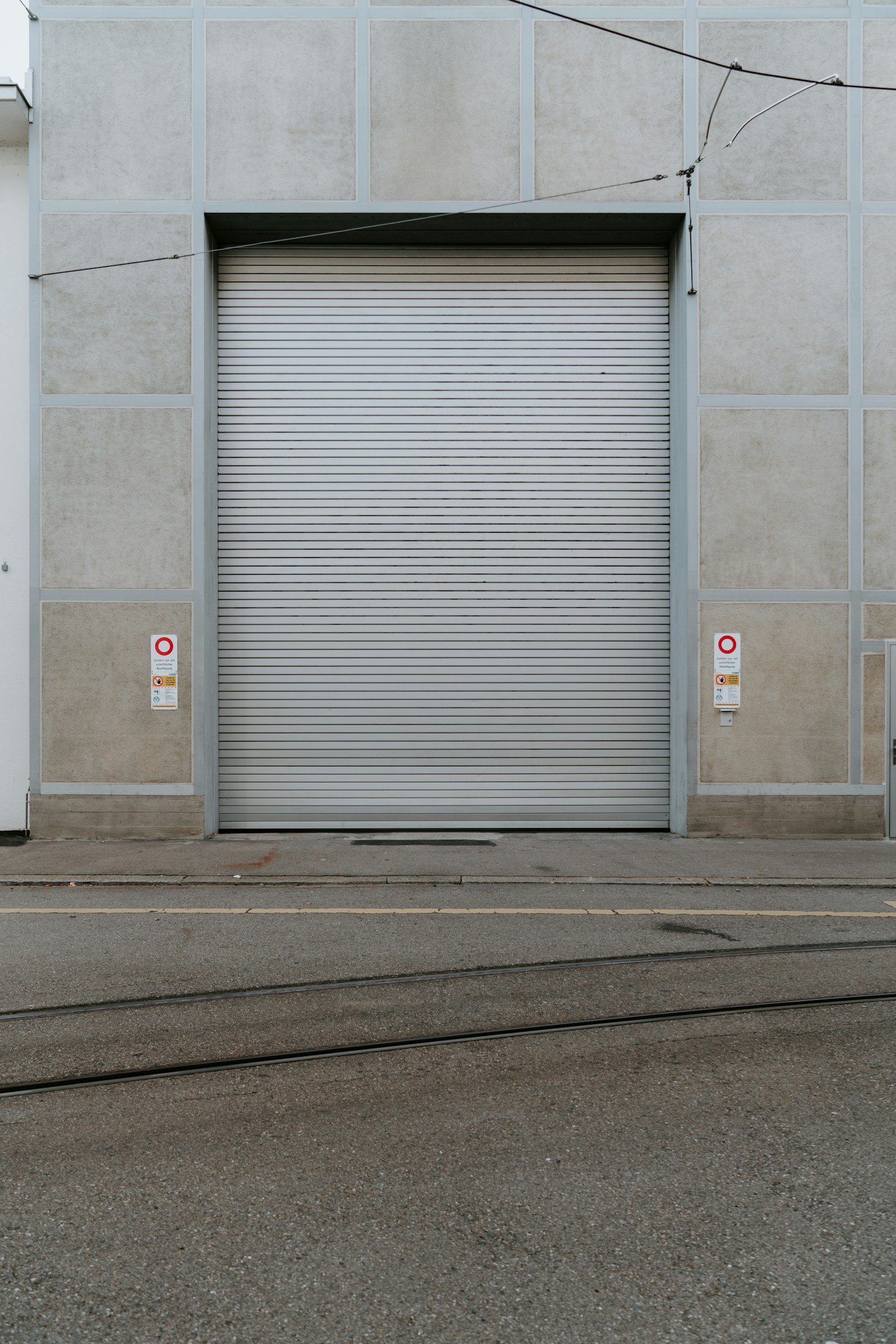 Porte rapide industrielle blanche installée par FERMIS sur façade béton — accès logistique professionnel
